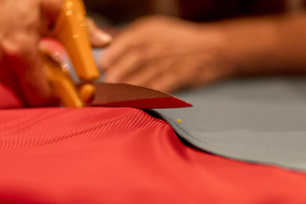Coupe d’un tissu rouge aux ciseaux de couturière